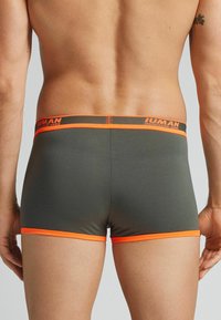 Szare bokserki z pomarańczowym pasem i wykończeniem. Gładki materiał, dopasowany krój i detal z logo na pasie.