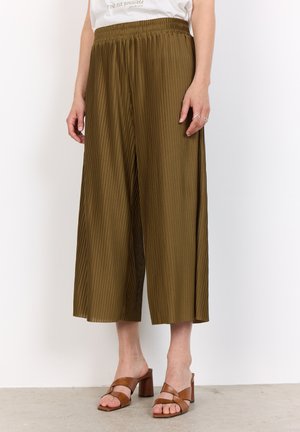 Olivengrüne, plissierte Culottes mit einem elastischen Bund, die eine lockere Passform und einen luftigen Stoff haben, kombiniert mit braunen, römischen Sandalen mit Blockabsatz.