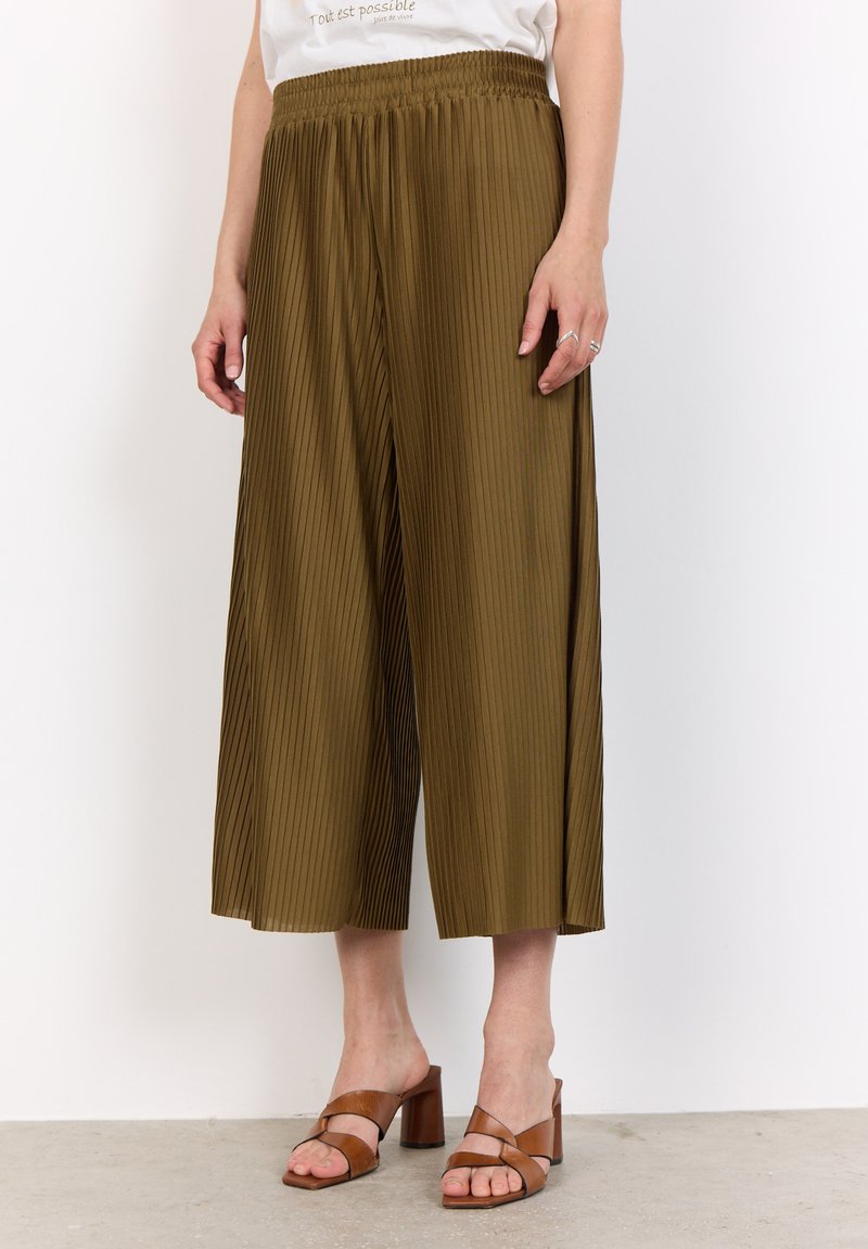 Olive green pleated culottes with an elastic waist, featuring a loose fit and flowy texture, paired with brown strappy block-heeled sandals.