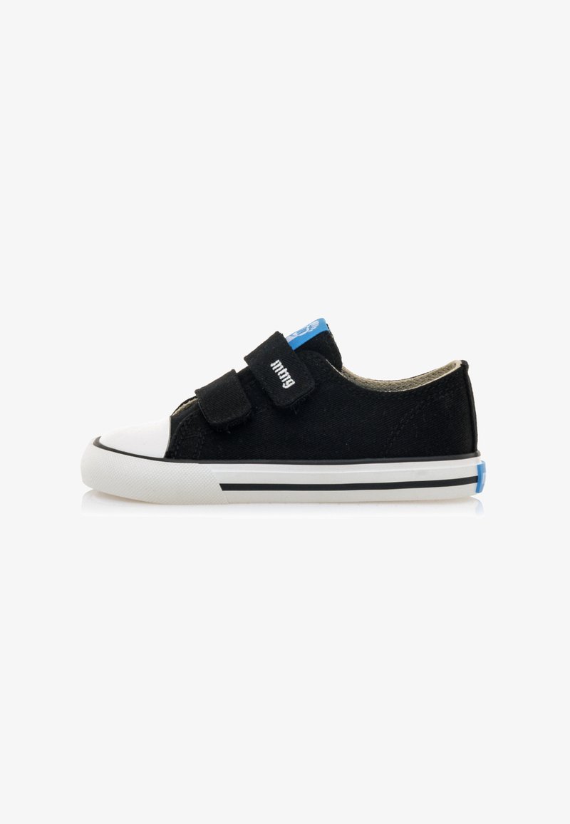 Zapatillas de lona negras con punta de goma blanca, dos correas de velcro ajustables y acentos azules en la lengüeta y el talón. Suela a rayas en blanco y negro.