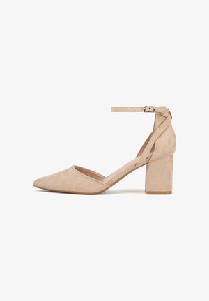 Scarpa con tacco alto in camoscio beige con punta a punta e tacco largo a blocco. Presenta un cinturino alla caviglia fissato con una fibbia argentata.