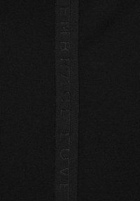 Svart stickad tyg med ett texturerat vertikalt streck som har präglad texten "OMFÖR KÄRLEK" i matchande färg. Slät textur överlag.