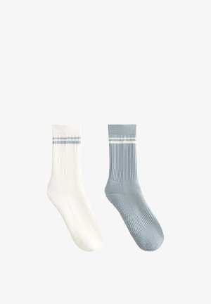 One white sock and one gray sock with white stripes near the top, ribbed texture and grip dots on the sole, displayed side by side.