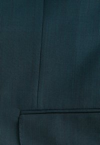 Dunkelblauer Stoff mit feiner gerippter Textur. Verfügt über eine Naht und ein kleines Taschen-Detail, das ein strukturiertes Design betont.