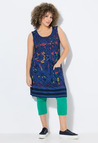 Granatowa, bezrękawnikowa sukienka z kolorowymi abstrakcyjnymi wzorami i dwoma kieszeniami. Połączona z zielonymi spodniami 3/4 i granatowymi sneakersami.