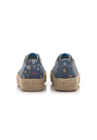 Chaussures en denim bleu avec broderies florales, semelles en jute texturé et dos doux. Forme ronde avec un design à enfiler.