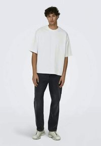 White, short-sleeve T-shirt, relaxed fit, paired with dark jeans and white sneakers. Simple design with no visible logos or patterns.
