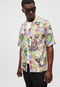 Kortærmet skjorte i letvægtigt stof med et farverigt blomster- og abstrakt mønster. Designet med spread collar og en enkelt brystlomme.