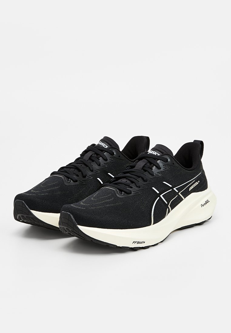 Zwarte sportieve schoenen met een getextureerde stoffen bovenkant, witte accenten en een dikke crème tussenzool. Beschikt over een vetersluitingssysteem en een gewatteerde kraag.