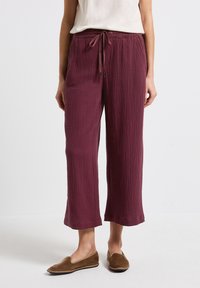 Bordeaux wijde-pantalon in gestructureerde stof met een elastische tailleband en koord. Vloerlange snit met een ontspannen pasvorm.