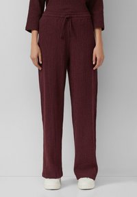 Bordeaux gebreide broek met een textuurpatroon, elastische tailleband en verstelbaar koord. Gecombineerd met witte schoenen, met een ontspannen pasvorm.
