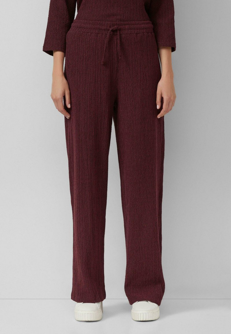 Bordeaux gebreide broek met een textuurpatroon, elastische tailleband en verstelbaar koord. Gecombineerd met witte schoenen, met een ontspannen pasvorm.