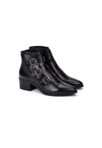 Botas negras de cuero hasta el tobillo con punta afilada, que cuentan con tres correas ajustables con hebillas doradas y un tacón cuadrado. Textura suave.