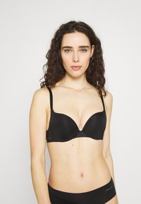 Black padded bra with smooth cups, adjustable straps, and a v-shaped center. Paired with matching black underwear.