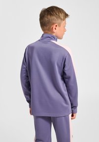 Paarse sportjas met een hoge kraag, contrasterende roze schouderpanelen en een gladde, lichtgewicht stoftextuur.