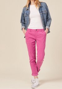 Pink cotton chinos with a straight cut, featuring a button fastening and side pockets, paired with a white t-shirt and denim jacket.