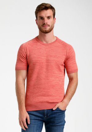 Suéter de manga corta y cuello redondo en tejido coral texturizado. Presenta puños y dobladillo acanalados. Lo lleva puesto con jeans de mezclilla azul.