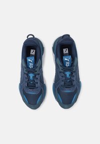 Chaussures de sport bleues composées d'un mélange de mesh et de daim, avec une semelle texturée et un accent bleu sur la languette et les lacets.