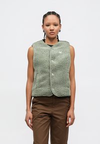 Zelená flísová vesta s textúrou a nadýchaným pocitom, zaobleným výstrihom, prednými gombíkmi a malým logom na hrudi.
