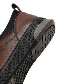 Baskets en cuir marron avec une tige élastique noire, semelle en caoutchouc texturée et un tirant au talon. Présente un motif de grip solide sur la semelle extérieure.