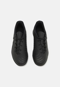 Baskets de sport noires avec une tige synthétique lisse, un design à lacets, des détails texturés et un bout légèrement arrondi.