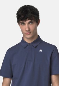Námornícky polo tričko s klasickým golierom, krátkymi rukávmi a nenápadným logom na hrudi. Hladká tkanina s jemnou textúrou.