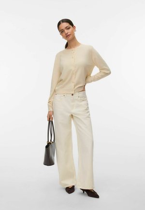 Light beige knitted cardigan with buttons, paired with creamy wide-leg trousers and black handbag. Textured fabric, clean design, casual fit.