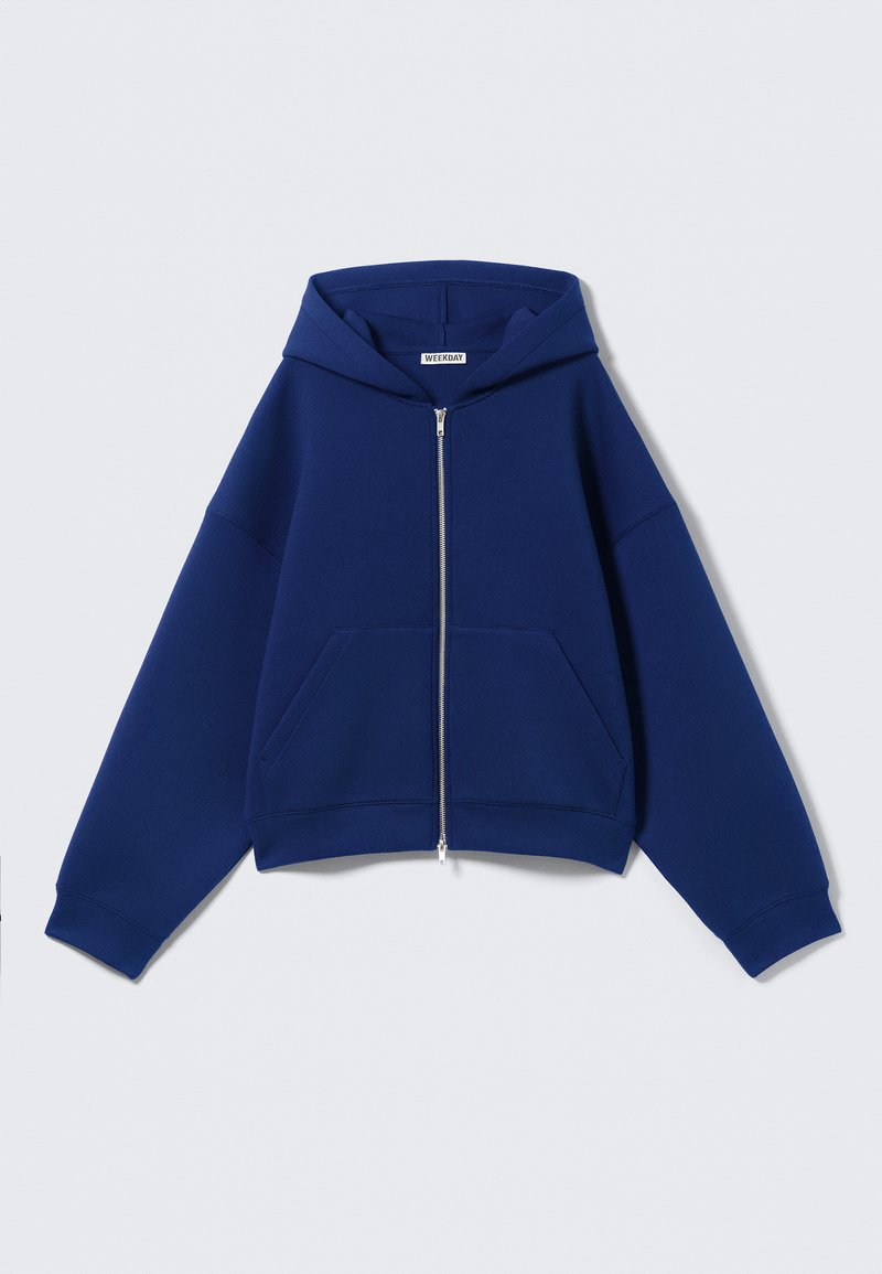 Sweat à capuche zippé bleu marine en tissu doux, doté d'une capuche spacieuse, de poches avant et de poignets côtelés avec une coupe décontractée et surdimensionnée.