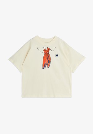 camiseta de manga corta color crema con un gráfico de una bufanda naranja atada en el cuello y una "M" azul bordada en el costado.