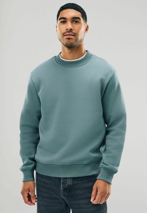 Lys teal sweatshirt i blødt stof, har en ribbet rund halsudskæring og manchetter, med en afslappet pasform og ensfarvet design. Sammen med mørke jeans.