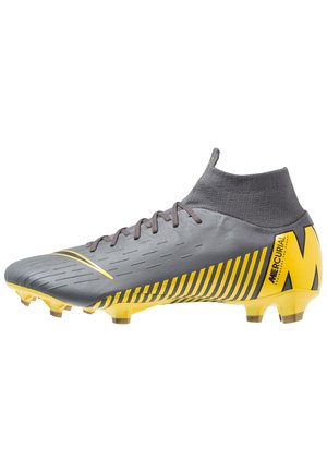 Crampon de football montante gris et jaune avec lacets, tige texturée et semelle cloutée pour terrain ferme, marque Mercurial.