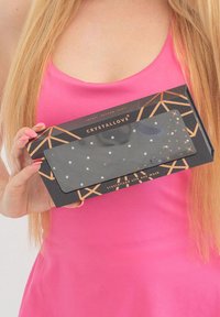 Packaging di una maschera per gli occhi nera con accenti geometrici dorati, caratterizzata da punti bianchi simili a cristalli. Il testo recita "CRYSTALLOVE" e "maschera per gli occhi in seta cristallizzata."