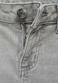 Grå denimjeans med framtida dragkedja, metallknapp stängning och synliga söm detaljer. Enfärgad tyg med lätt textur.