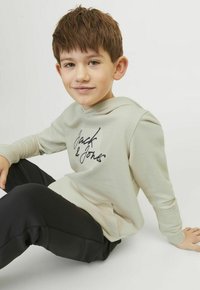Felpa grigia chiara con logo nero "Jack & Jones", tasca a marsupio, polsini a coste, abbinata a pantaloni neri. Tessuto liscio, design casual.