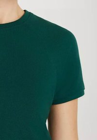 Zielona koszulka z krótkim rękawem i okrągłym dekoltem, wyróżniająca się teksturowanym materiałem i dopasowanym krojem. Szczegóły szwów są widoczne na ramionach.