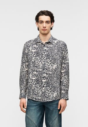 Skjorte med knapper foran i marineblå og cremefarvet abstrakt mønster, lange ærmer og klassisk krave. Bruges med blå teksturerede jeans.