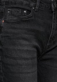 Mustat farkut, joissa on hieman haalistunut rakenne, viiden taskun muotoilu, metalliset yksityiskohdat ja suora leikkaus.