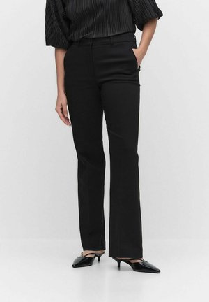 Black tailored trousers with a straight leg, featuring a smooth fabric and side pockets. Worn with a black pleated top and pointed heels.