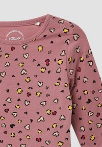 Lila lange mouw babyshirt met drukknoopjes op de schouder, versierd met kleine rode, gele, zwarte en beige hart- en bloemafdrukken.