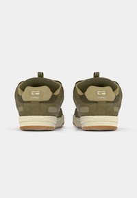 Adidași verzi din suede și plasă, cu o talpă cu amortizare, având un manșon de prindere și branding pe călcâi. Accentele texturate îmbunătățesc aderența.
