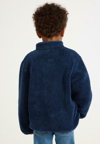 Marineblauer Fleece-Pullover mit hohem Kragen und langen Ärmeln, der aus einem weichen, strukturierten Stoff gefertigt ist. Die Rückansicht zeigt ein lockeres Fit-Design.