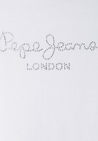 Balta kokvilnas t-krekls ar sudraba rhinestone dizainu, kas veido uzrakstu "Pepe Jeans LONDON", izsvītrots ar kursīvā stilā. Gluda tekstūra.