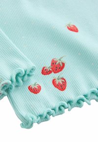 Vaaleansininen ribbineulospinta, jossa on pieniä valkoisia pilkkuja, punaisilla mansikkakuoseilla ja röyhelöreunuksilla.