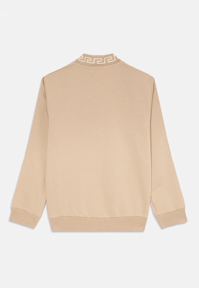 Beige Sweatshirt mit einem gerippten Kragen, der ein weißes griechisches Schlüssel-Muster aufweist. Lange Ärmel und eine glatte, weiche Textur.
