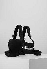 Černá krosbody taška s nastavitelnými popruhy, polstrovaným tělem a výrazným bílým logem "ellesse". Texturovaná tkanina se zipovým uzavřením.