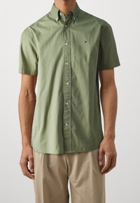 Korte mouwen knoopshirt van lichtgroene katoenfabricage, met een puntige kraag en een subtiele logo op de borst. Gladde textuur.