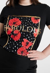Camiseta negra de manga corta con un gráfico colorido de amapolas rojas y un diseño de estampado de leopardo, acentuada con letras doradas que dicen "FABULOSO."