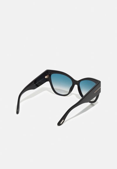 Sorte solbriller med gradient blå linser, vinkelret kattøyeform, blank plastramme, gulldetalj på armene, og et elegant generelt design.