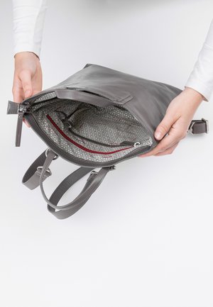 Graue Lederhandtasche mit einem Reißverschluss. Das gefütterte Innere weist ein geometrisches Muster und eine rote Akzenttasche auf. Zwei Träger sind sichtbar.