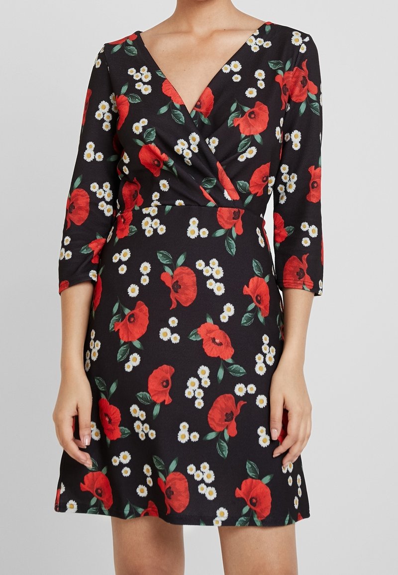 Robe noire avec un décolleté en V, manches 3/4, ornée d'un imprimé floral de coquelicots rouges et de marguerites blanches, fabriquée en tissu lisse avec une silhouette ajustée.